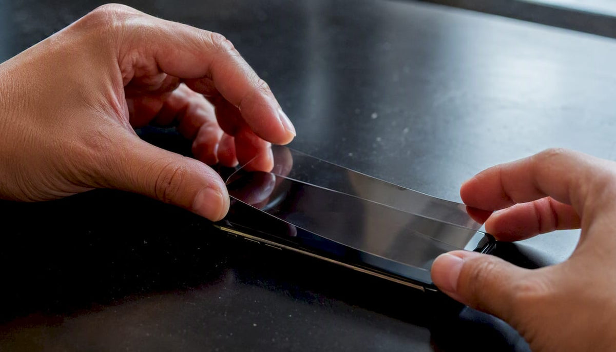 Hands applying ceramic screen protector on curved phone