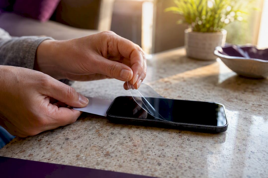 Hands peeling smartphone screen protector slowly