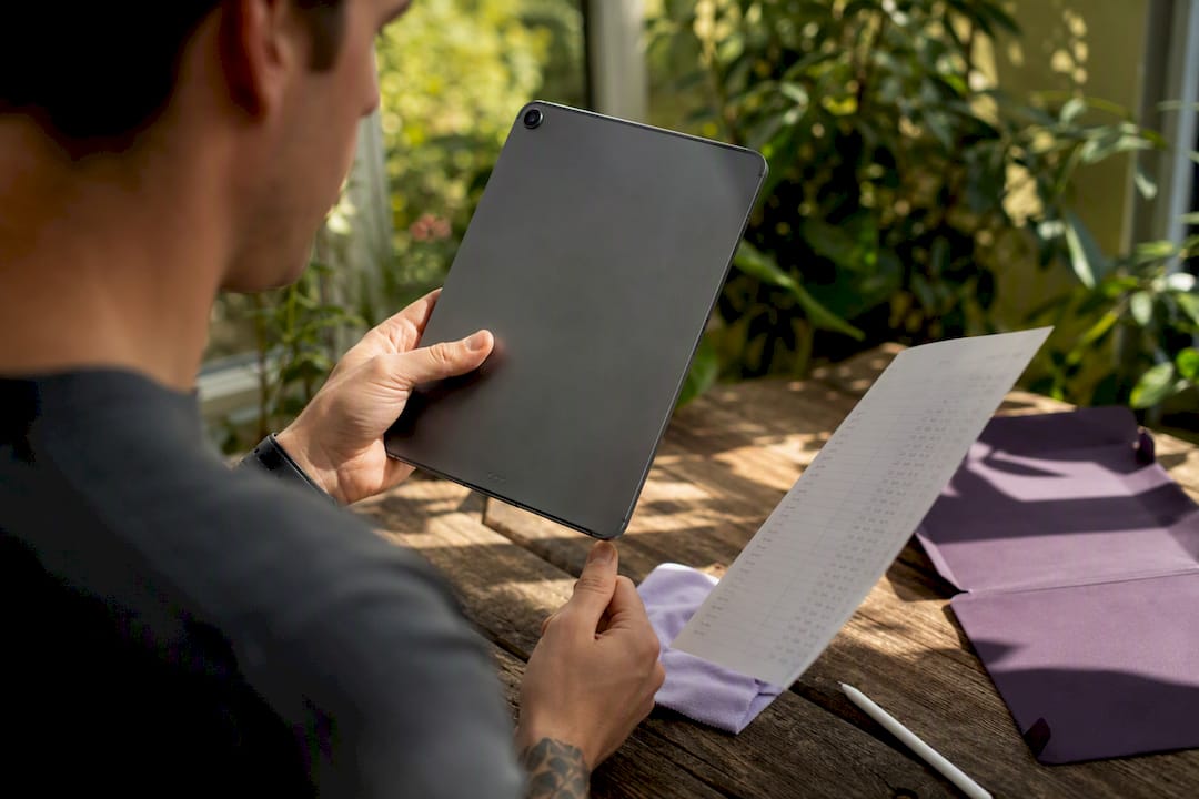 Person checking iPad model number on white desk