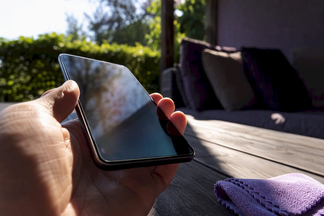 Hand tilting phone screen in bright sunlight