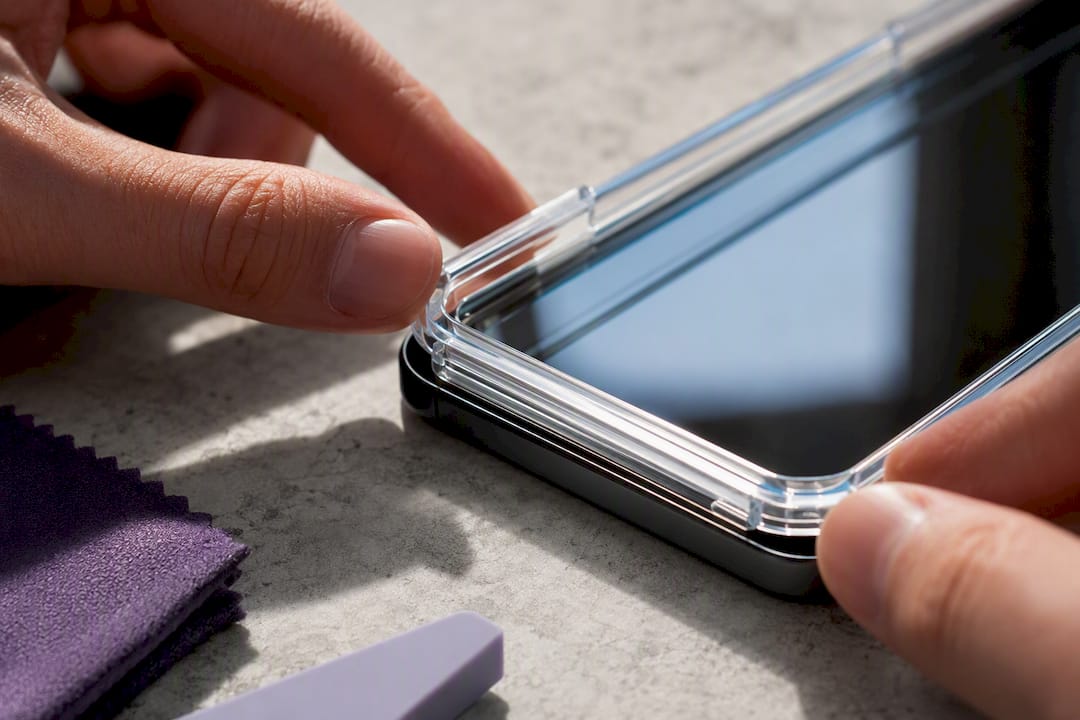 Hands positioning a screen protector frame