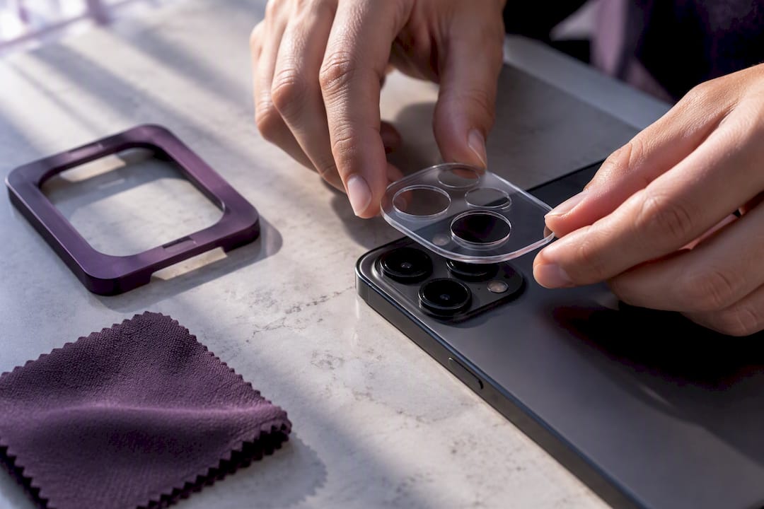 Hands aligning lens protector over camera module